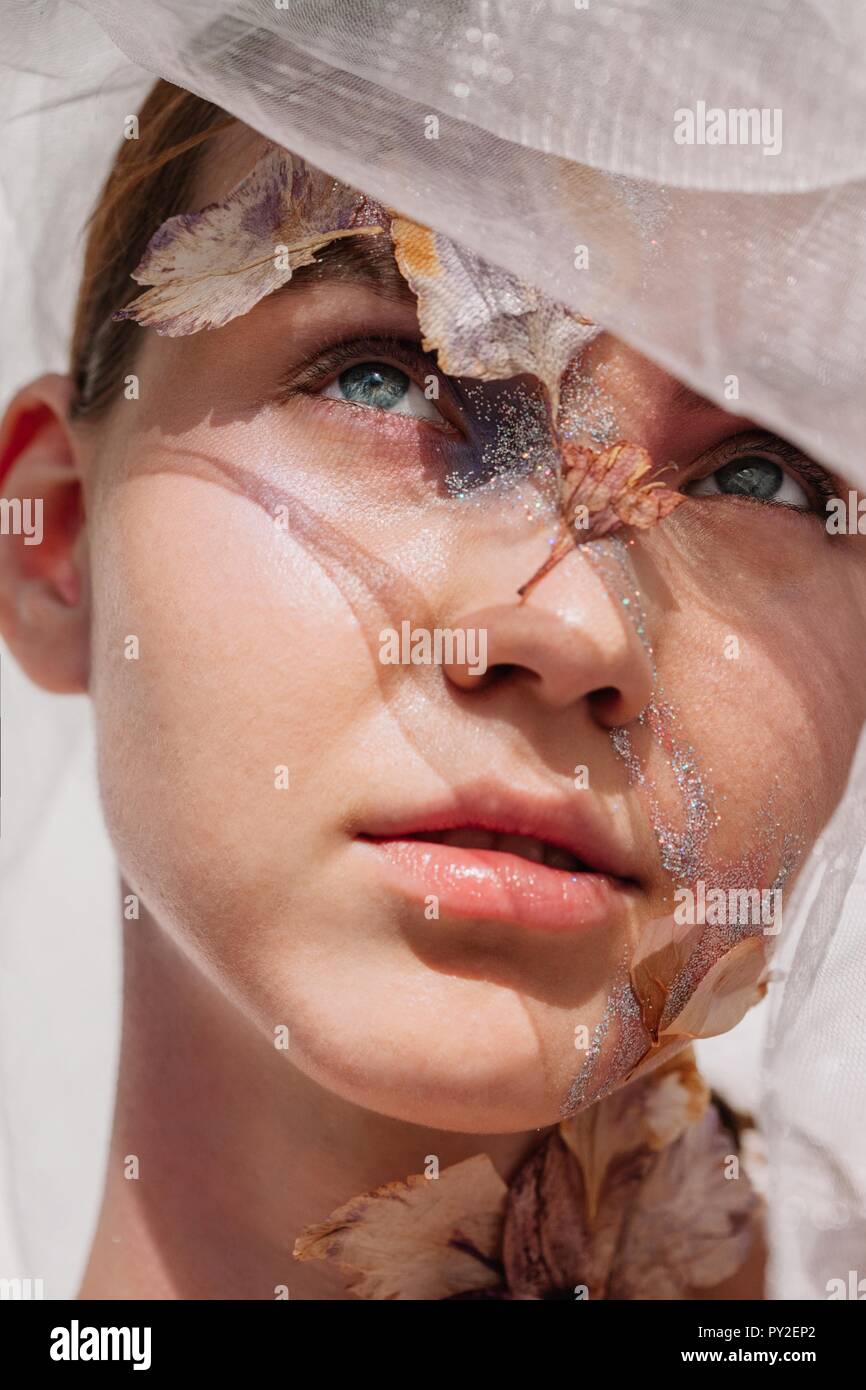 Conceptual beauty portrait of a woman wearing a veil with dried flowers on her face and neck Stock Photo
