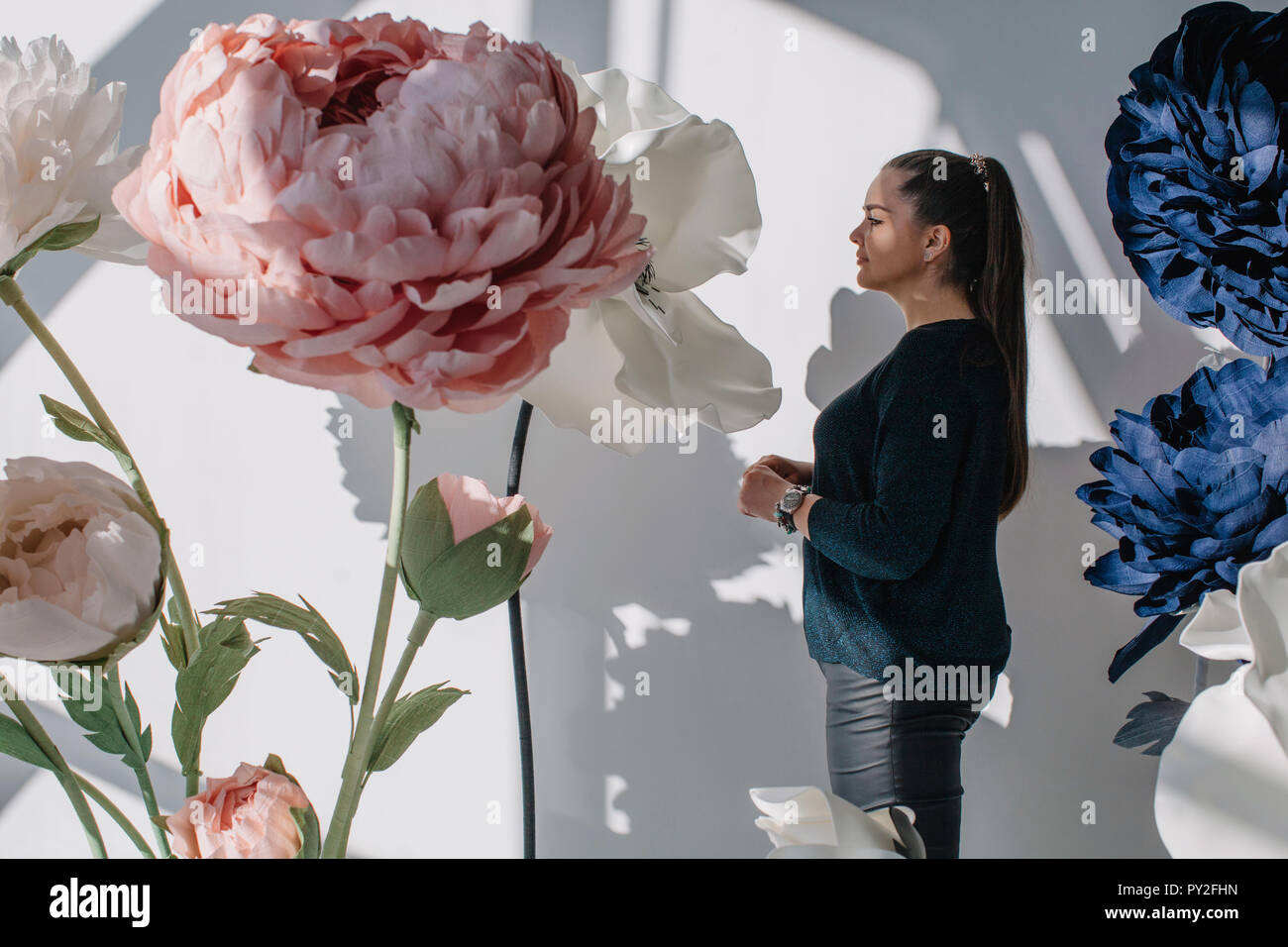 Portrait of a woman standing next to giant artificial flowers Stock Photo
