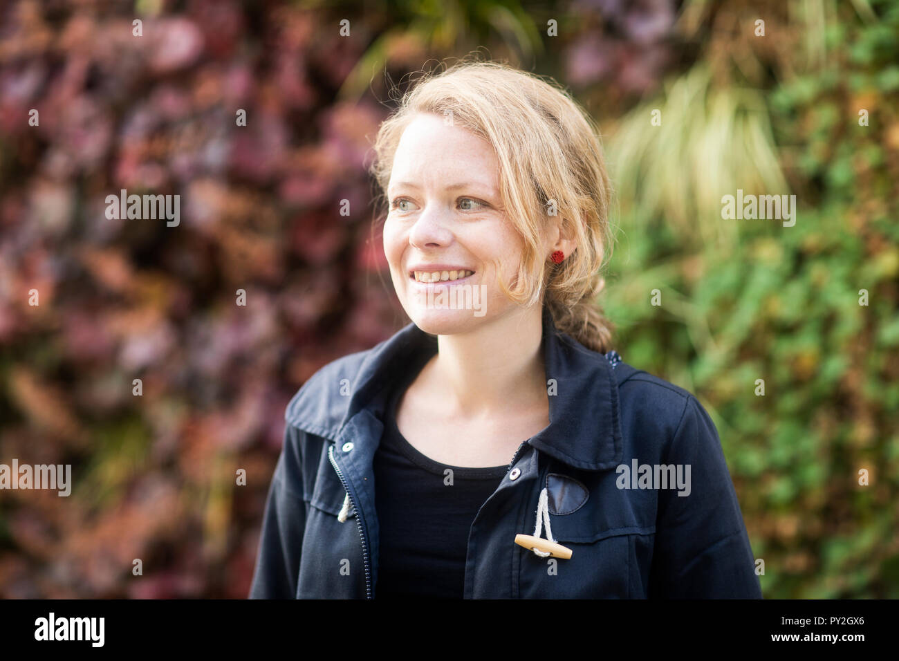 Portrait of a smiling woman standing in a public park Stock Photo - Alamy