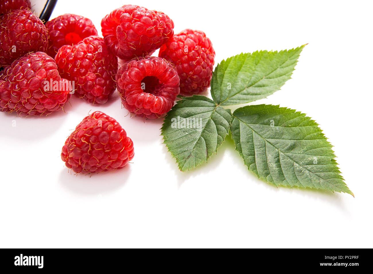 Close up view of white cup with fresh raspberries fruits and big green ...