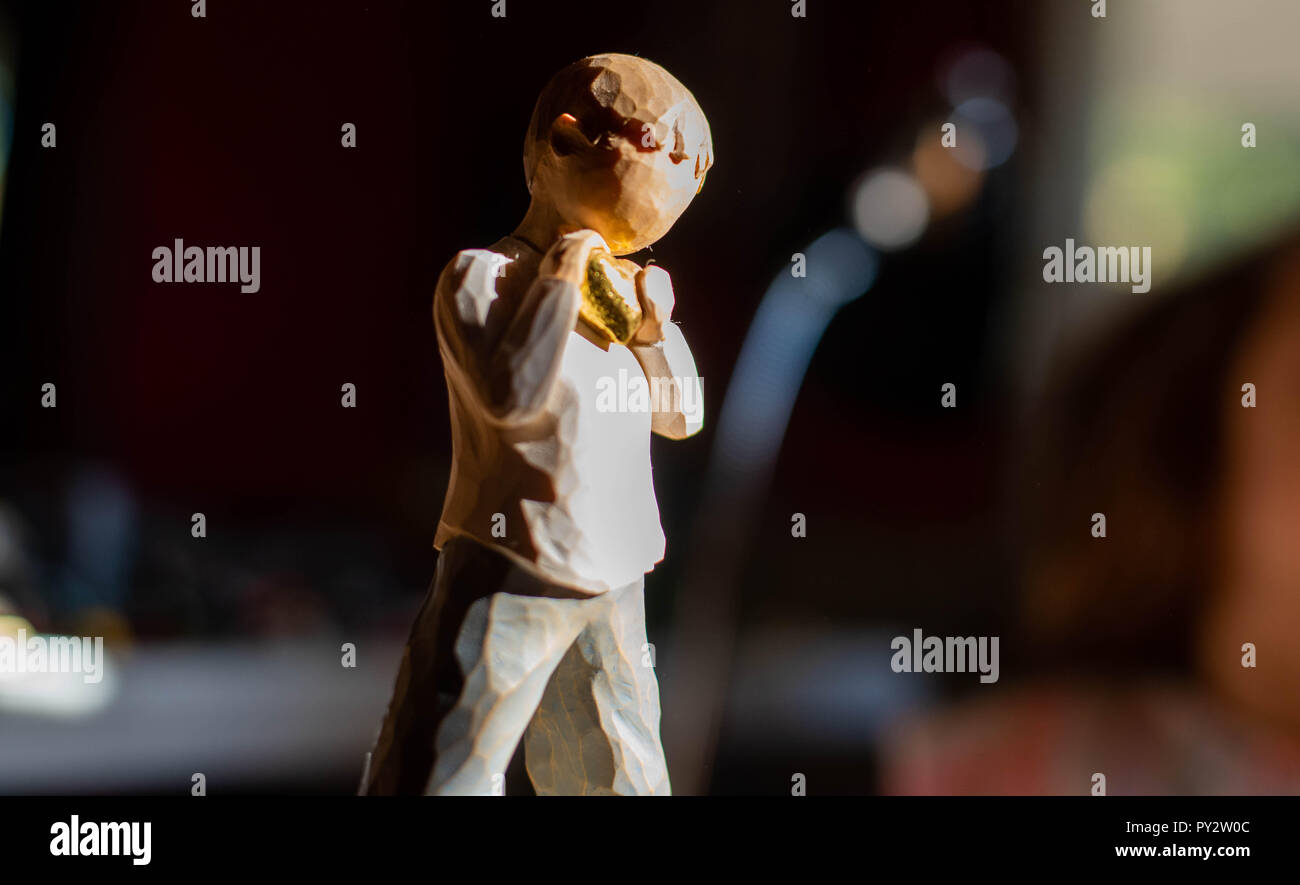 A small wooden statue of a child holding a golden heart. Stock Photo