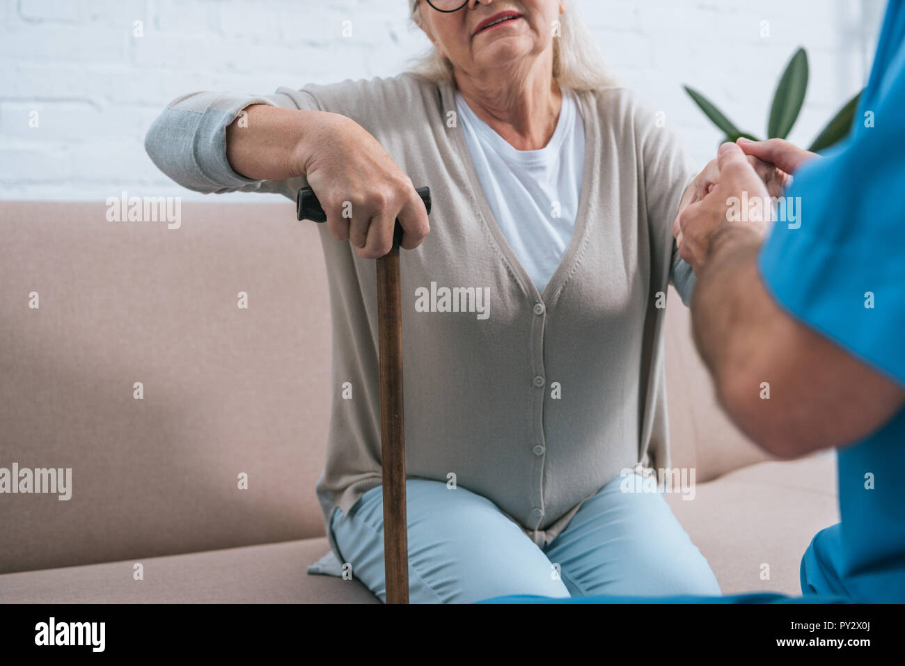 Cropped Shot Of Male Nurse Helping Senior Woman With Walking Stick