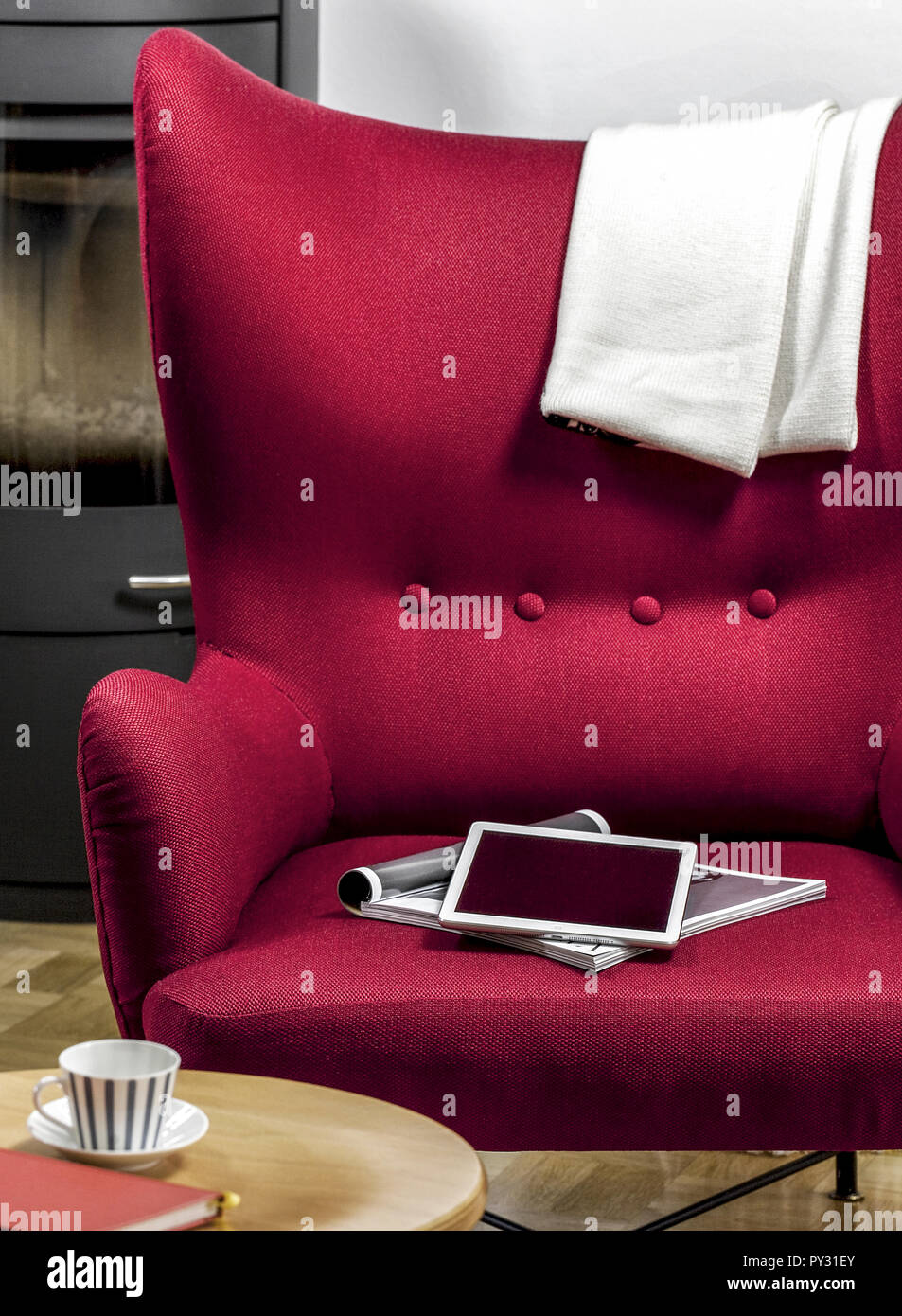 Tablet-PC und Zeitschrift liegen auf rotem Sessel Stock Photo