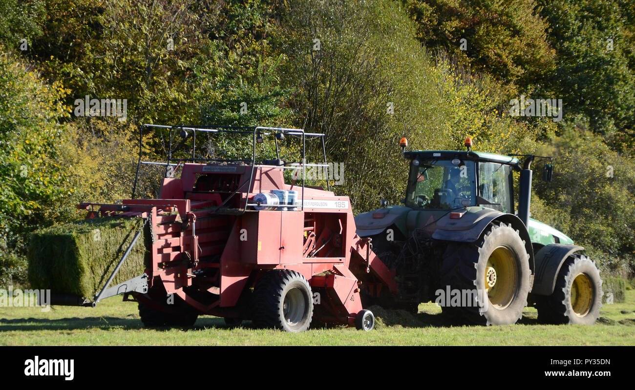 Sonderborg, Denmark - October 18, 2018: Tractor with baler collects fresh cut grass. Stock Photo