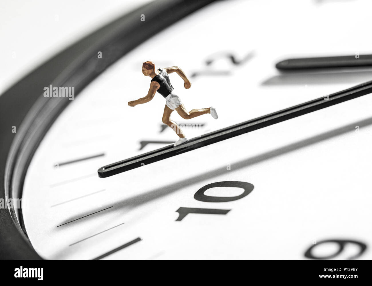 Symbol fuer Die Zeit rennt, Laeuferfigur auf Uhrzeiger Stock Photo