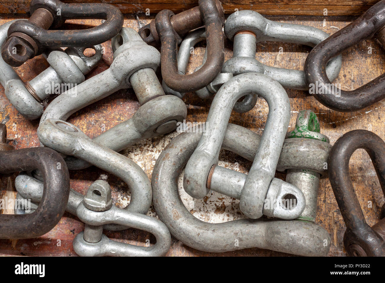 A selection of shackles of various sizes on a well used workbench Stock Photo