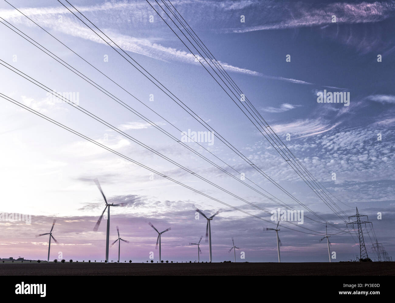 Windkraftturbinen und Ueberlandleitungen im Morgenlicht Stock Photo
