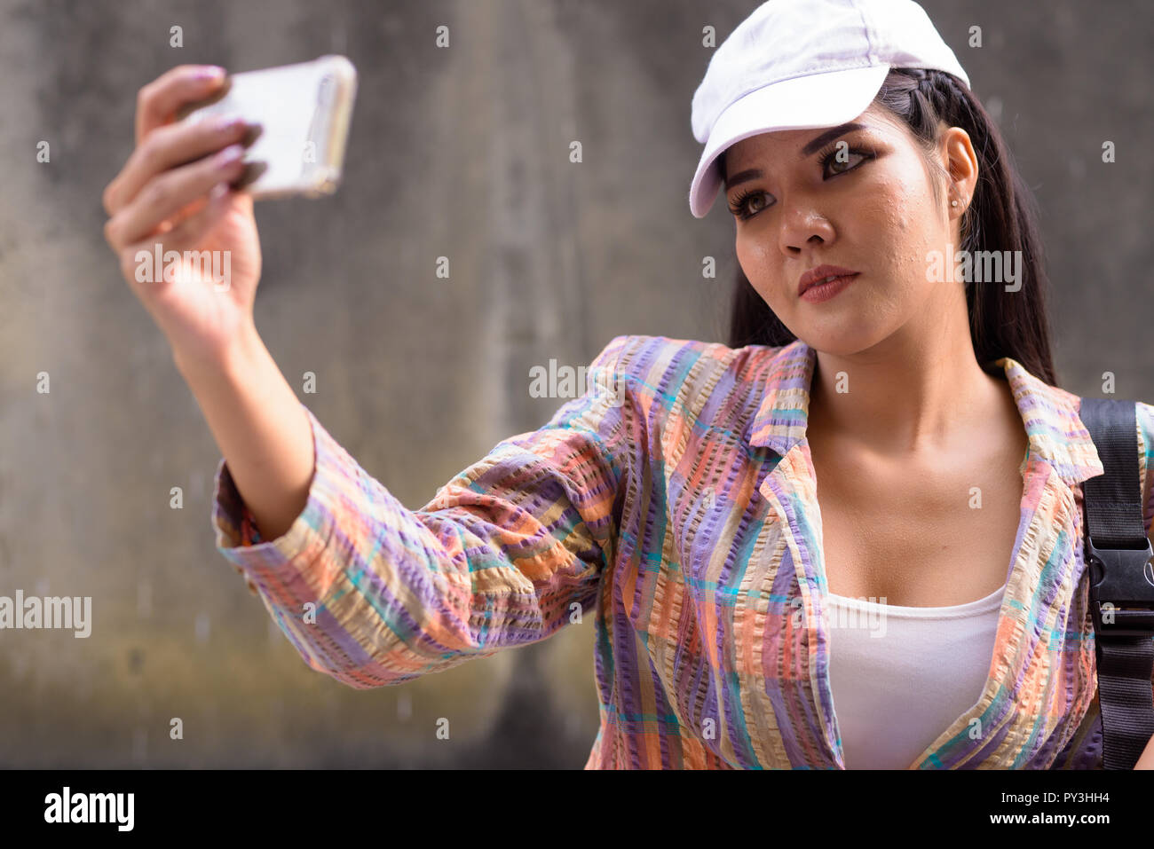 Beautiful Asian woman taking selfie using mobile phone outdoors Stock Photo