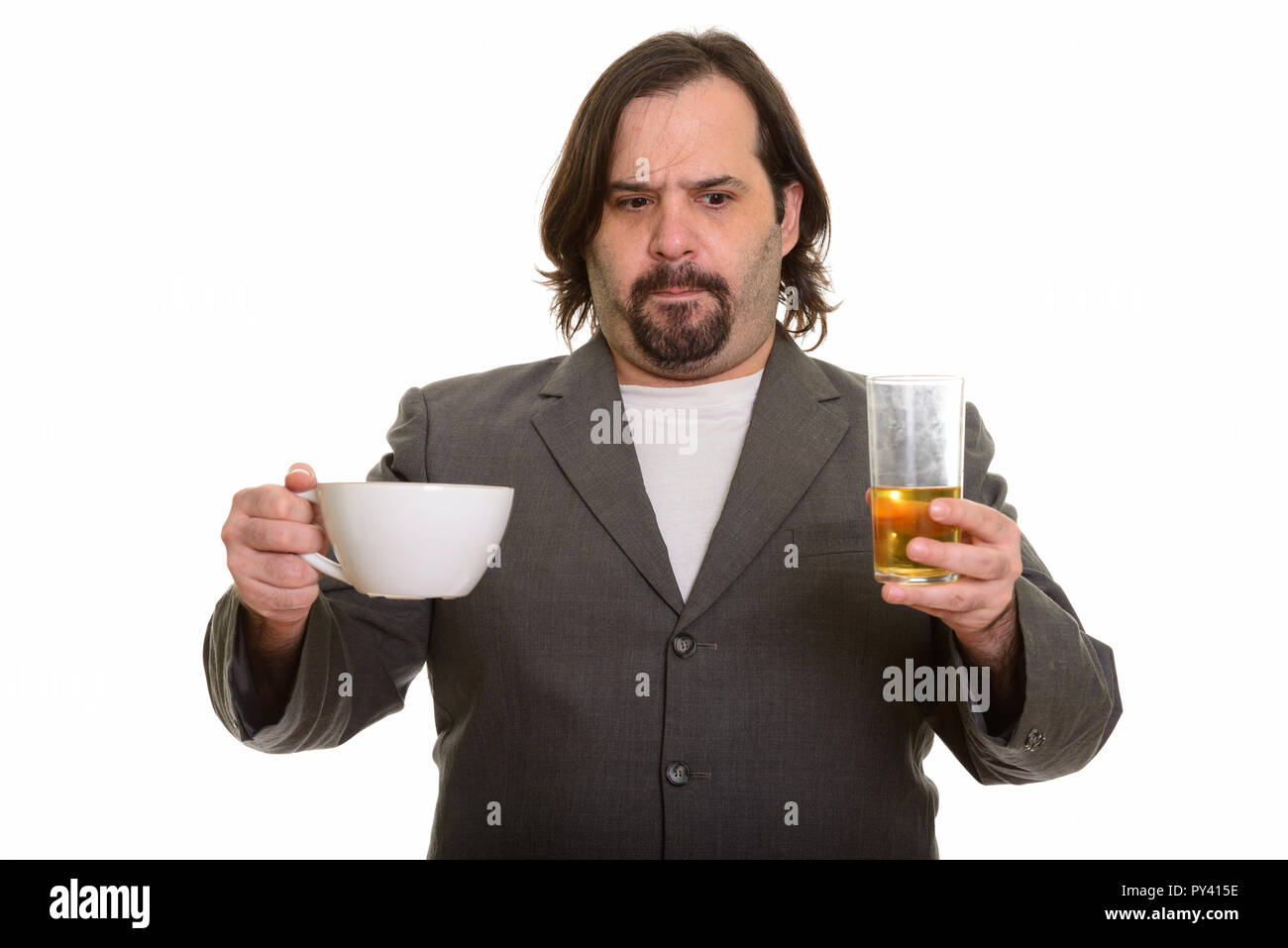 Fat Caucasian businessman choosing between coffee and beer Stock Photo