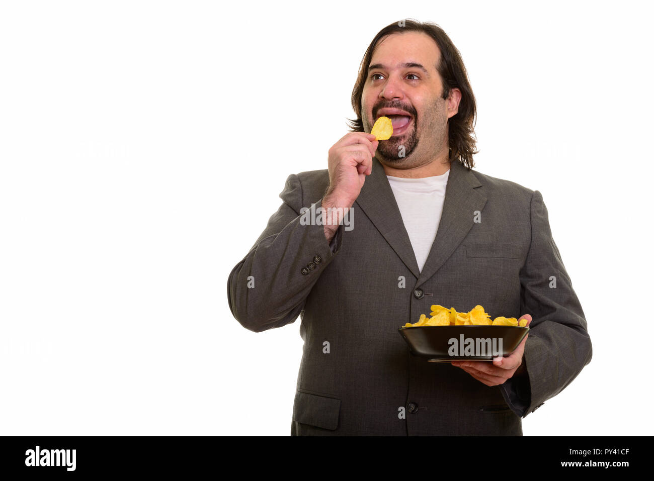 Happy fat Caucasian businessman smiling while eating chips  Stock Photo