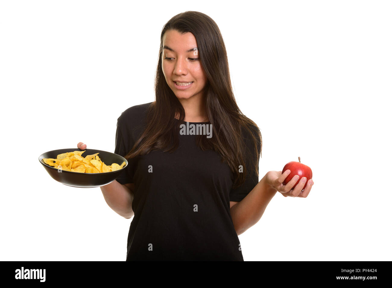Young Caucasian woman choosing between bowl of potato chips and  Stock Photo