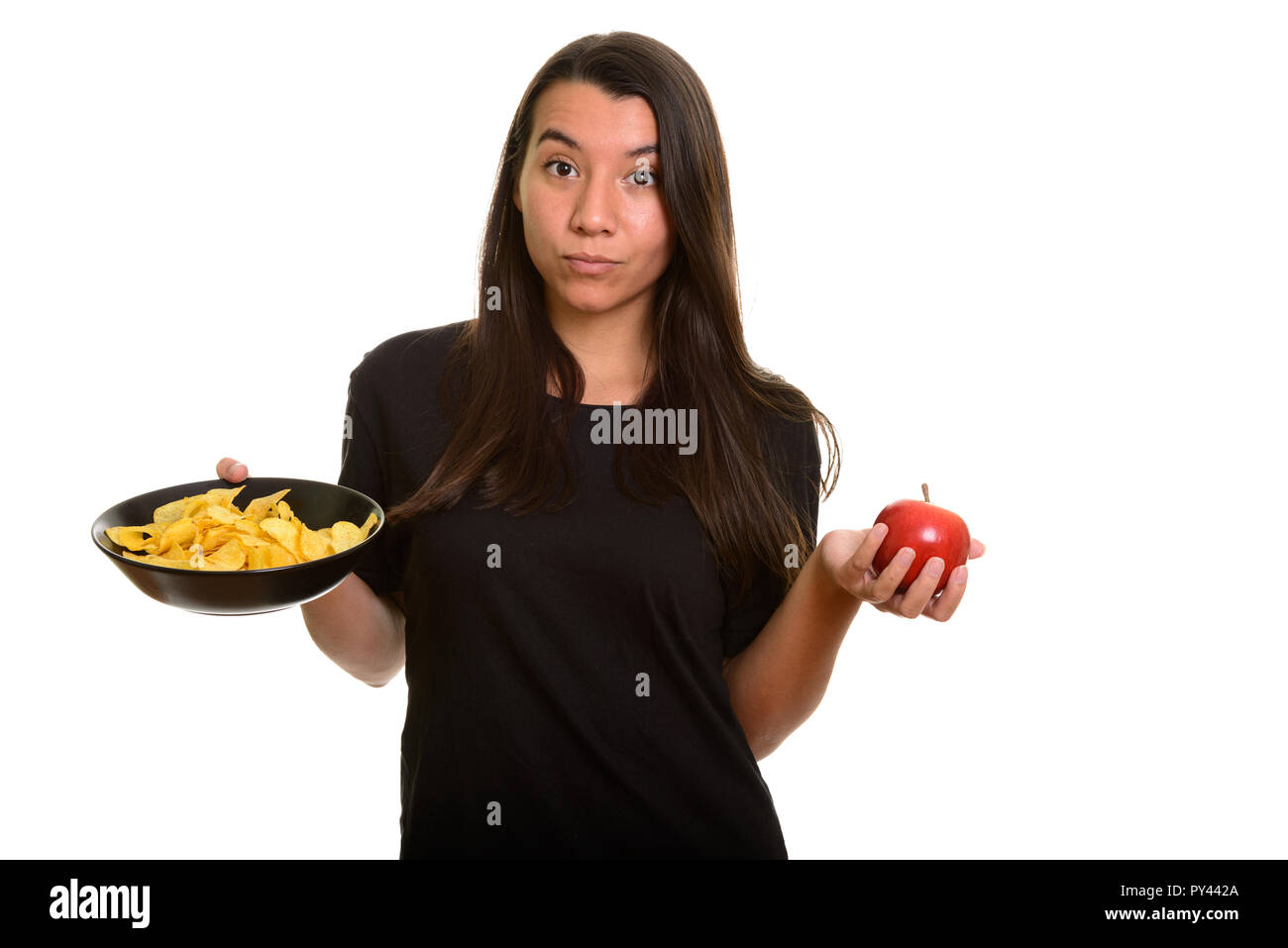 Young Caucasian woman holding bowl of potato chips and red apple Stock Photo