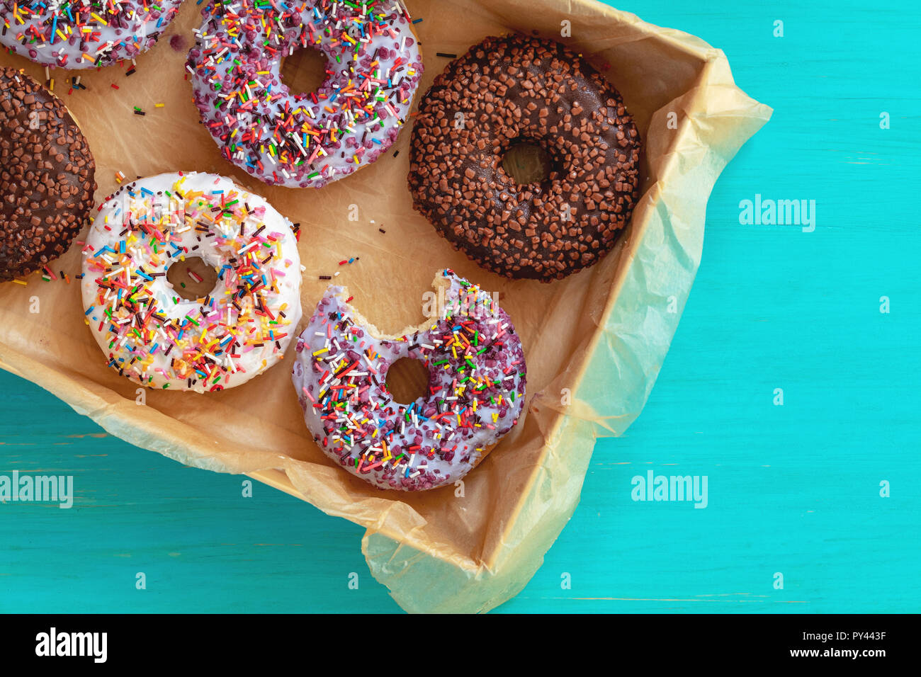 Delicious glazed donuts in box on turquoise blue surface. Flat lay ...