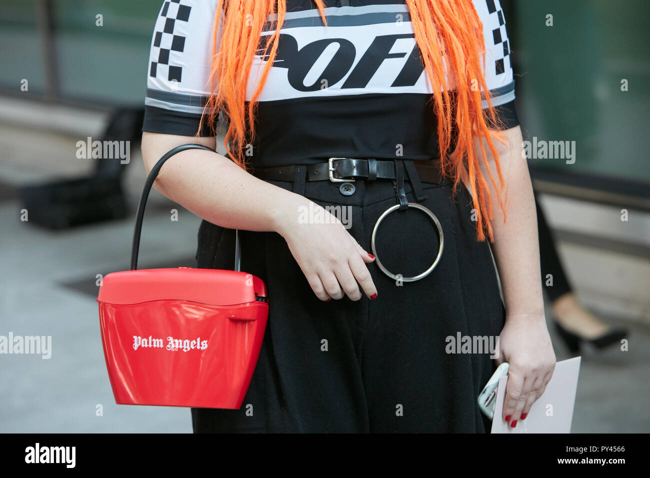 MILAN, ITALY - SEPTEMBER 23, 2018: Woman with red Palm Angels bag and orange hair before Giorgio Armani fashion show, Milan Fashion Week street style Stock Photo