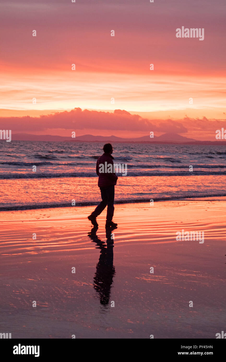 Evening walk on Black Rock sands as the sunsets over the Llyn Peninsula Snowdonia, North Wales Stock Photo