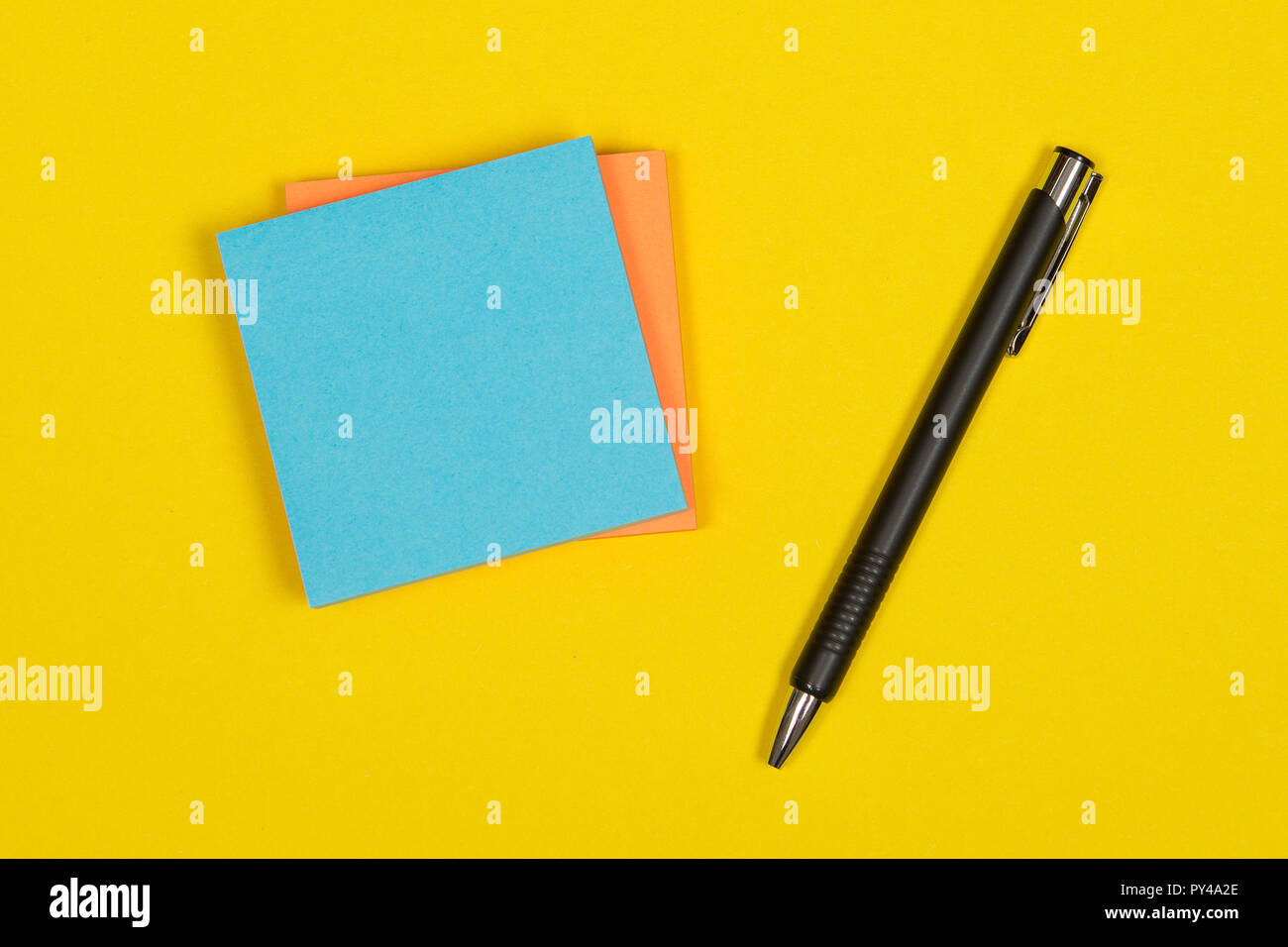 Colorful postit notes with pen on a yellow background Stock Photo
