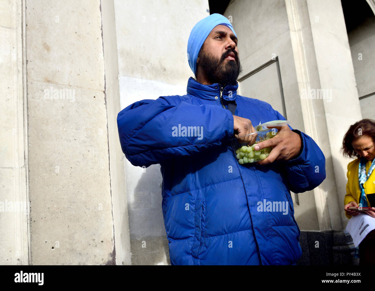 Sikh man eating grapes from a plastic box, central London, England, UK. Stock Photo