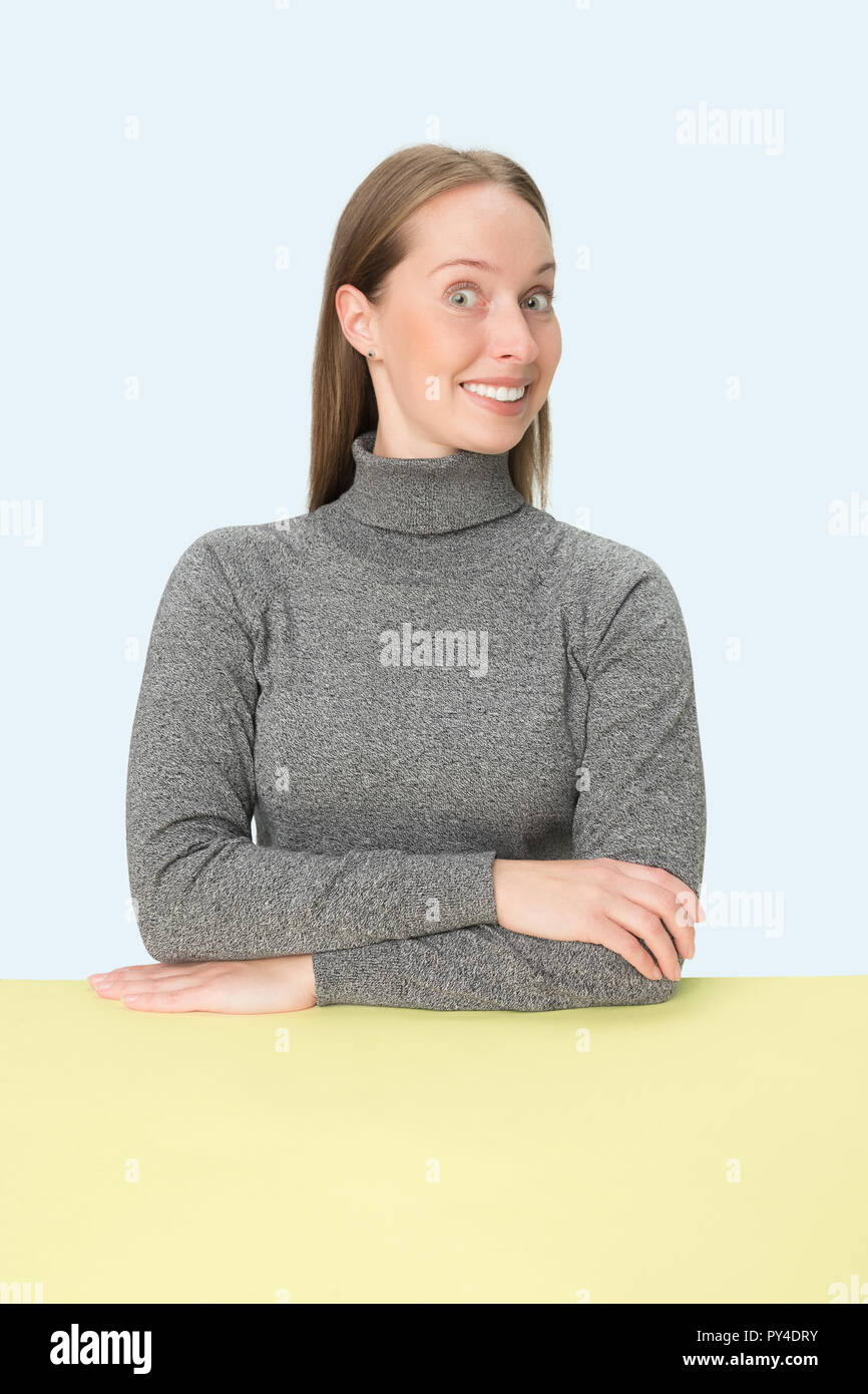 The happy and smiling business woman sitting at table on a pink studio ...