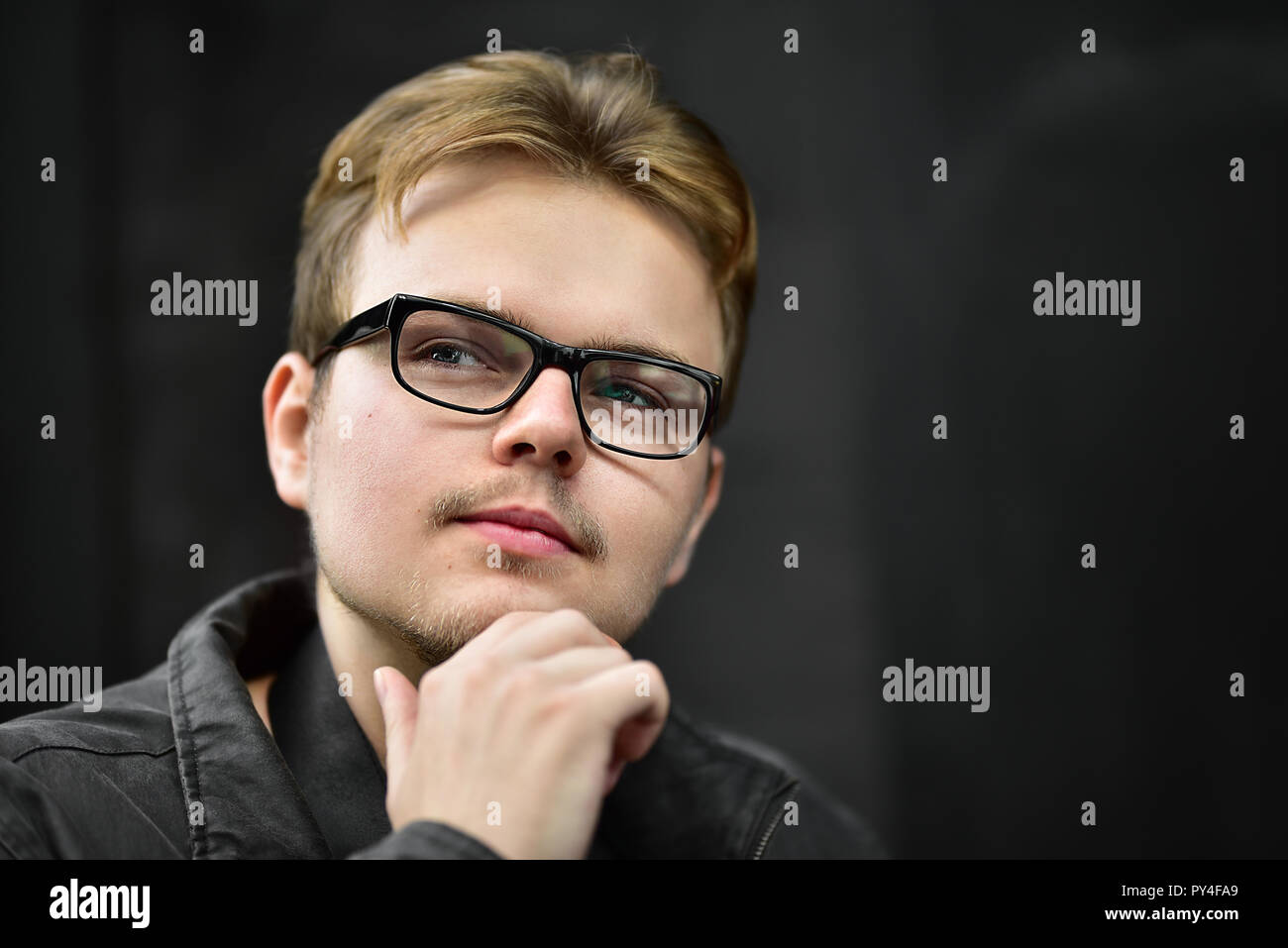 Serious young caucasian man wearing black glasses looking up and thinking Stock Photo