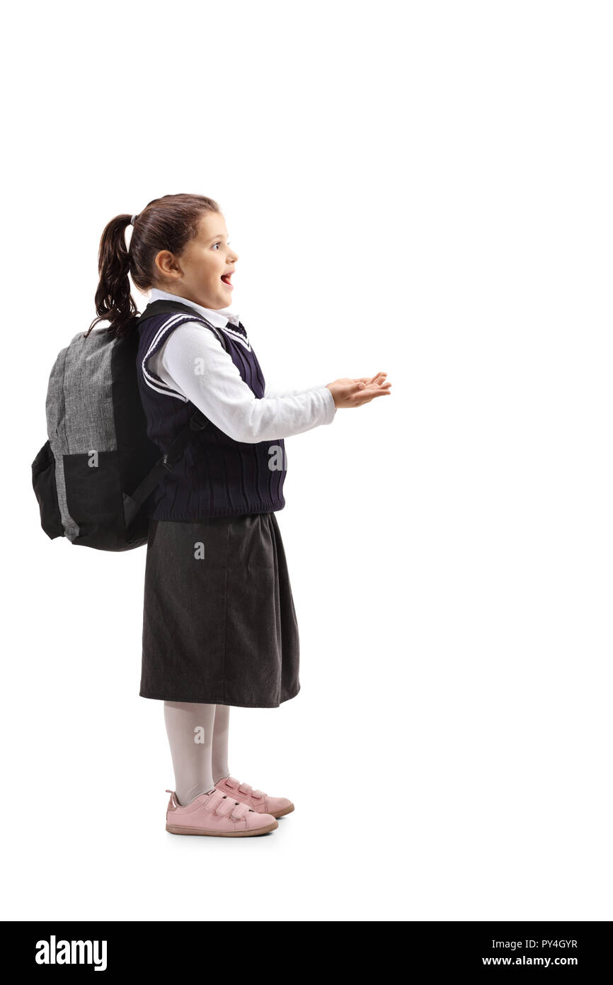 Full length profile shot of a surprised little girl in a school uniform holding her hands in front of her isolated on white background Stock Photo