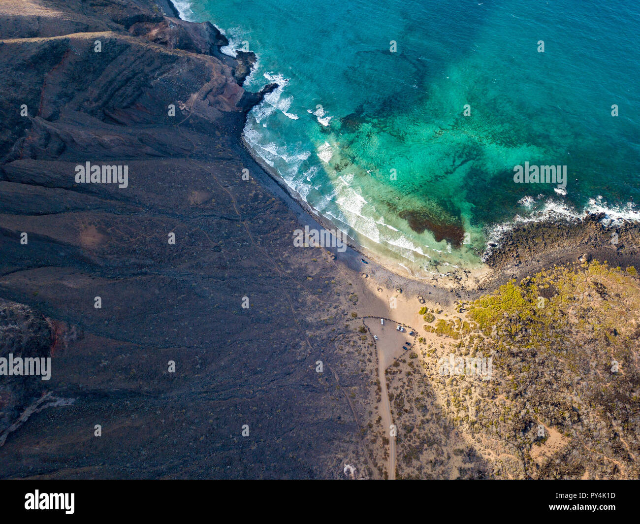 Aerial view of a crystal clear sea with waves and surfers. Playa De La Canteria. Orzola, Lanzarote, Canary Islands. Spain. Waves crashing on the beach Stock Photo