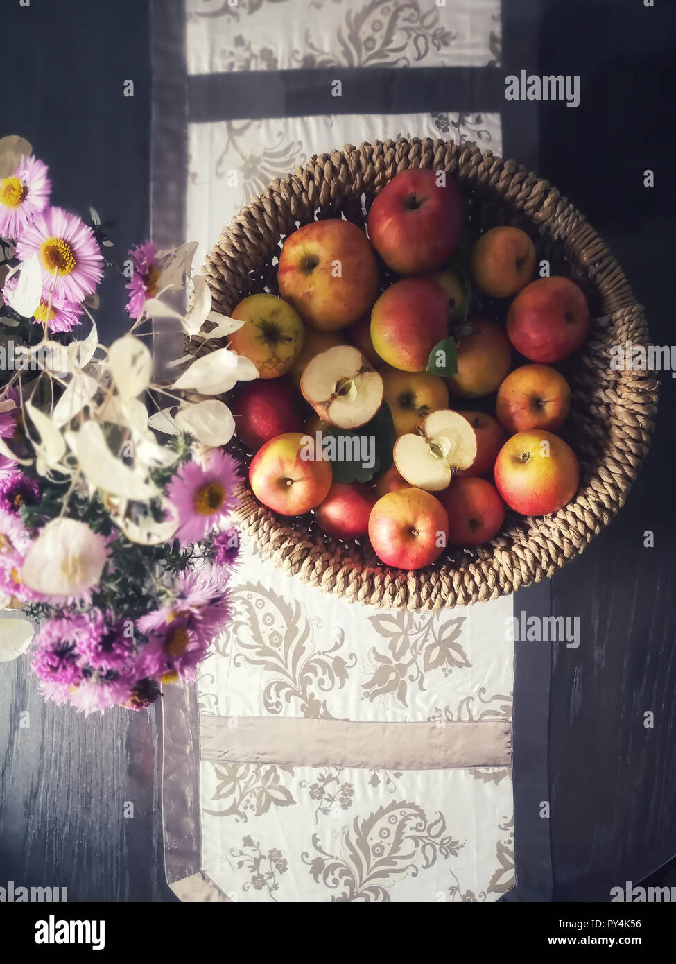 Organic apples are in a basket. 'Asters' and 'lunarias' are autumn flowers. Seasonal elements photographed from above. Stock Photo