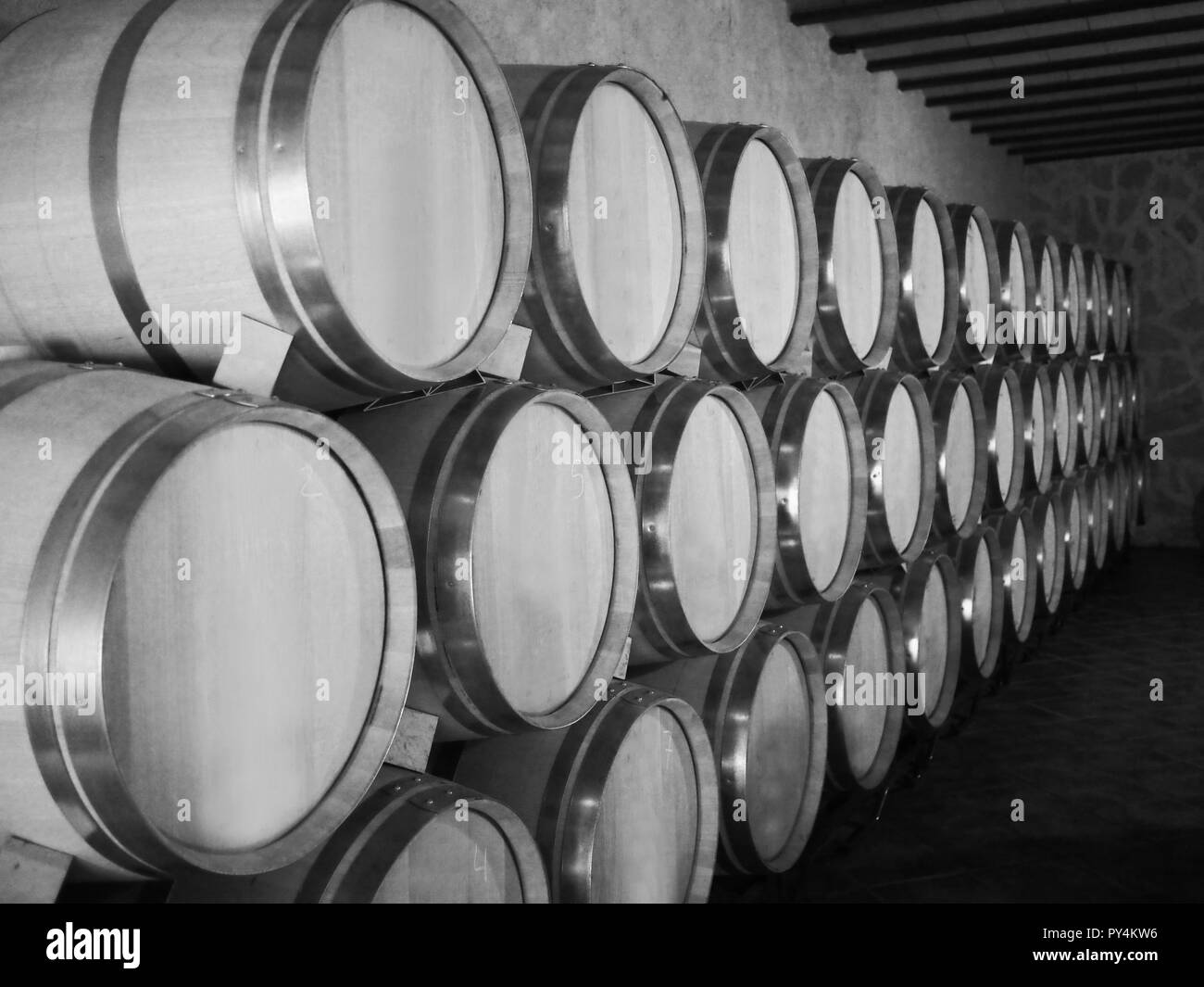 Old wine barrels in a wine cellar. Stacked up wine bottles in the