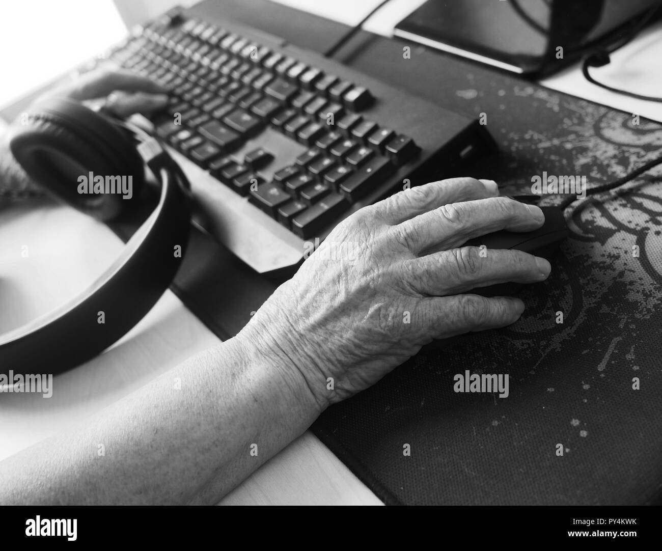 Old woman holding smartphone in her hands. Elderly woman looking at a smart phone inside her home Stock Photo