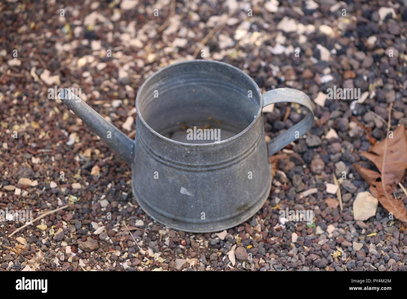 watering can. Tin garden watering can on the ground. Stock Photo