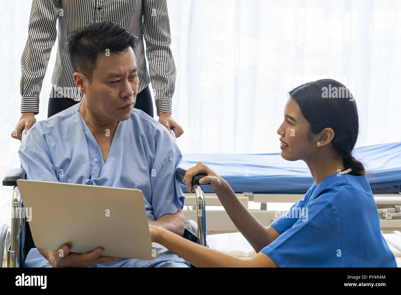 Physical therapist explain treatment method to senior patient and relative using notebook Stock Photo