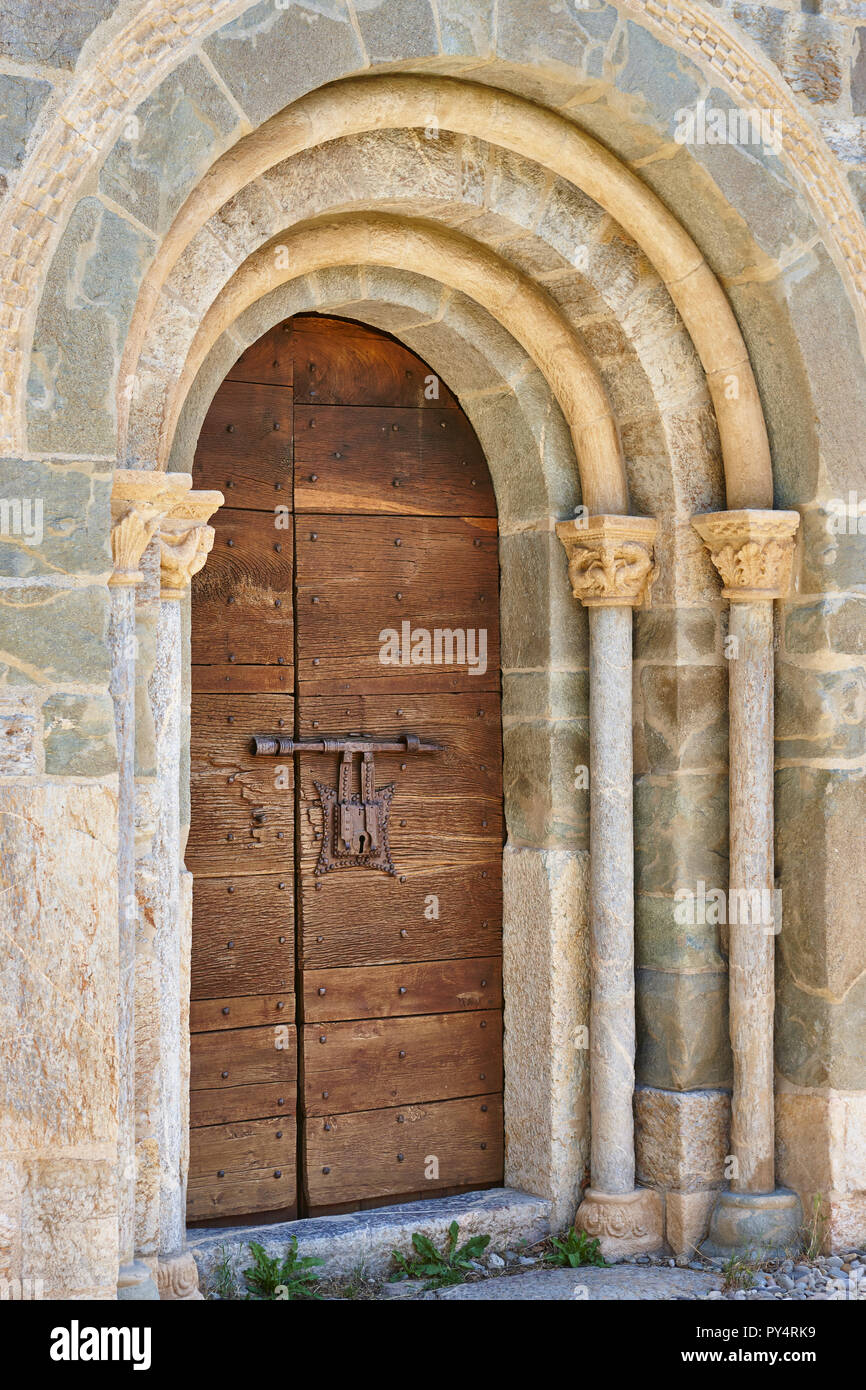 Romanesque entrance arch and capital with antique wooden door. Spain Stock Photo