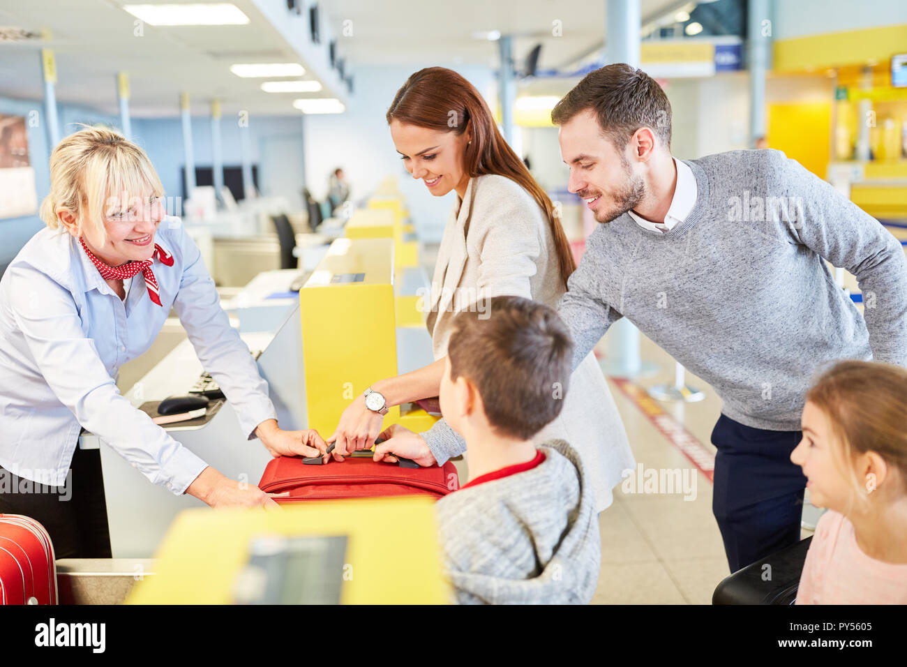 Family with children at the check-in desk in the airport drop off their ...