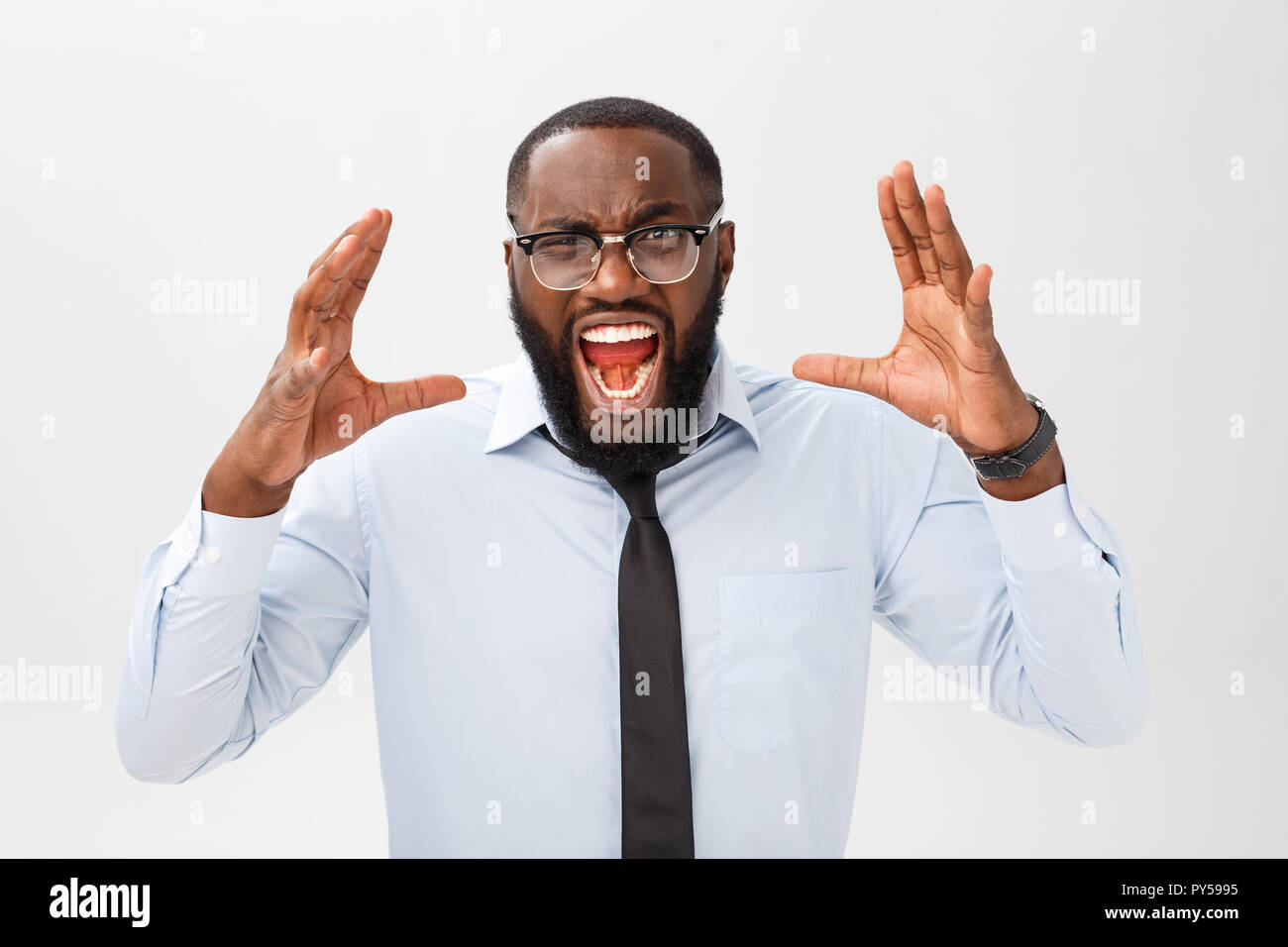 Portrait of desperate annoyed black male screaming in rage and anger tearing his hair out while feeling furious and mad with something. Stock Photo