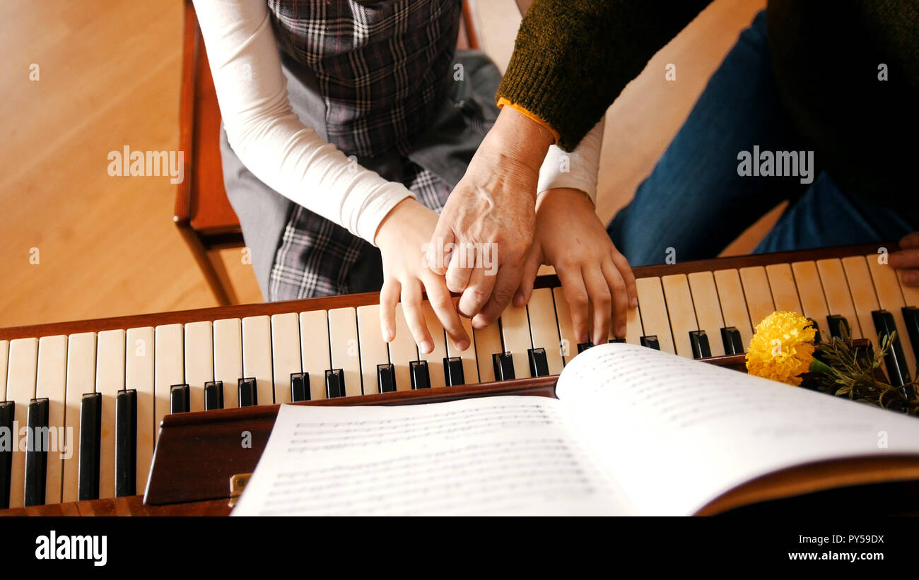 A little girl playing piano on music lesson. A teacher helping her. Hands Stock Photo Alamy