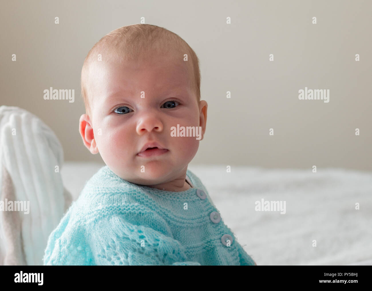 Little baby sitting on bed and looking at the camera close up of face portrait Stock Photo Alamy