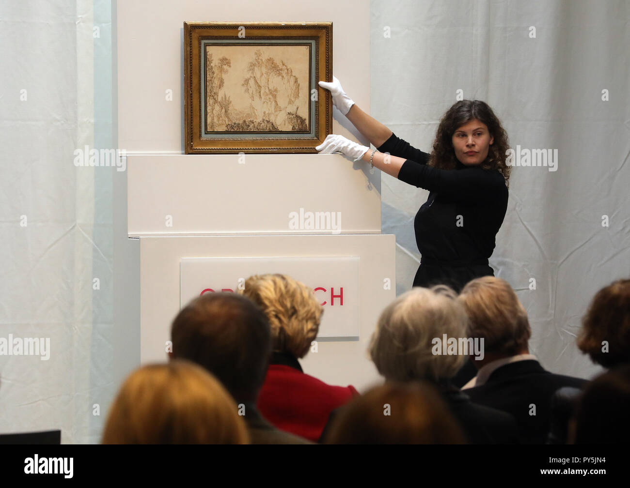Berlin, Germany. 25th Oct, 2018. An employee of the auction house Grisebach presents at the auction of the collection of the art dealer Bernd Schultz in the auction house Grisebach a Dutch picture with the title 'Mountain landscape with pilgrimage on a narrow path' about 1600 century. The entire proceeds will be donated to the planned Exilmuseum in Berlin. (to dpa 'Kunsthändler verkauft Privatsammlung für Exilmuseum' of 25.10.2018) Credit: Wolfgang Kumm/dpa/Alamy Live News Stock Photo