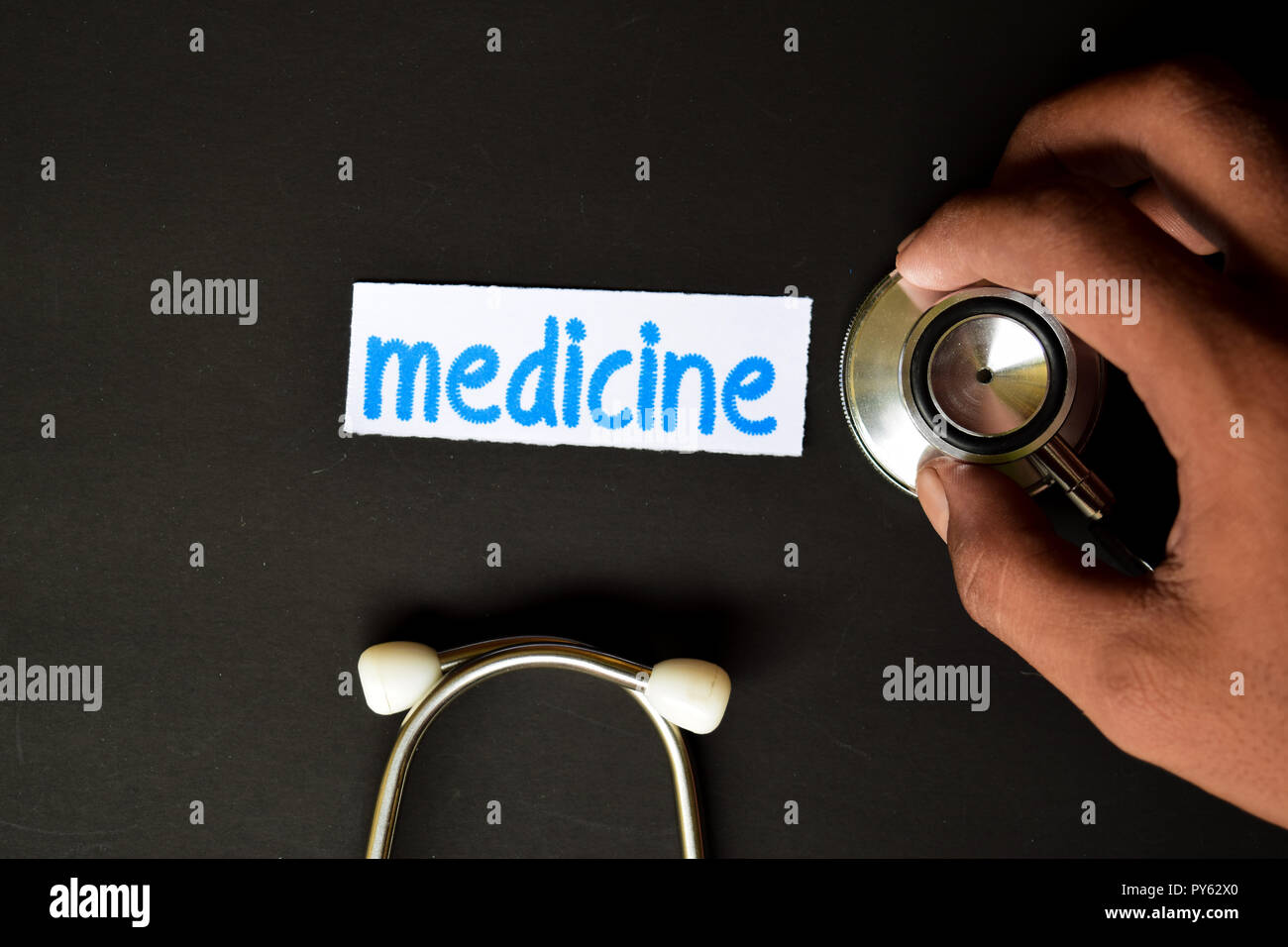 Conceptual image with Medicine inscription with the view of stethoscope, in someone hand with black background. Medical Conceptual. Stock Photo