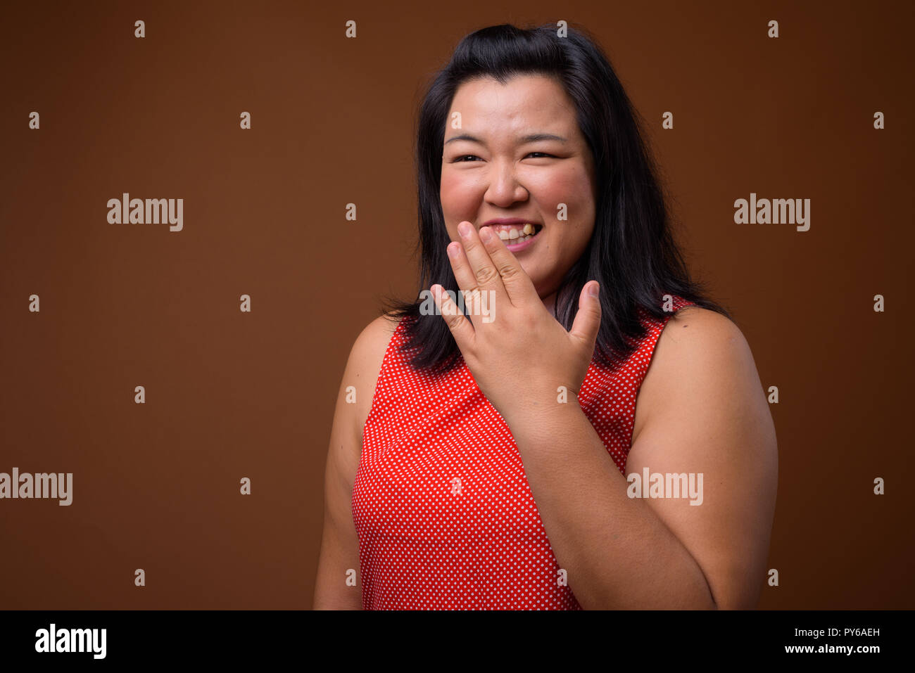 Happy beautiful overweight Asian woman laughing and covering mouth Stock Photo