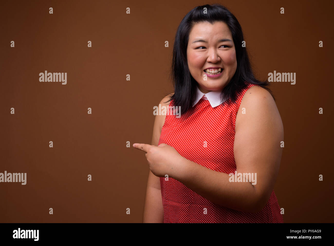 Beautiful overweight woman laughing and pointing finger to copy space Stock Photo