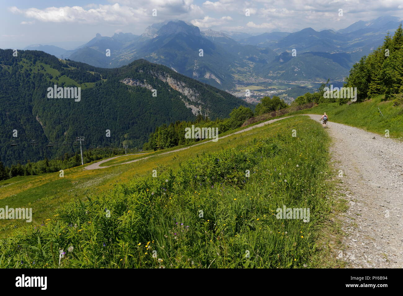 Female hiker on one of the trails with a view towards Faverges and distant mountains La Sambuy mountain area near Faverges France Stock Photo