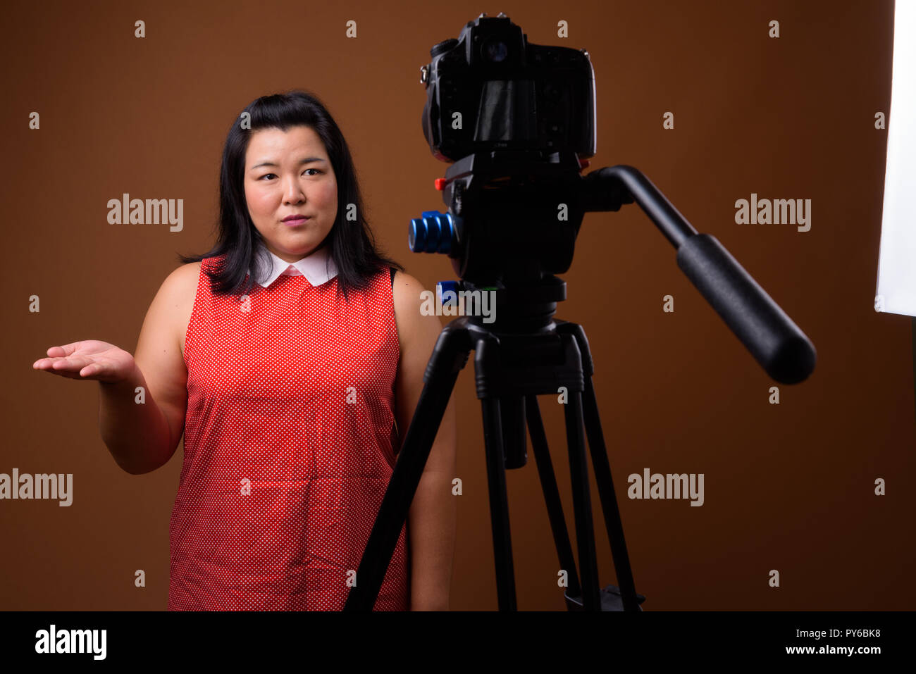 Overweight Asian woman vlogging in studio with dslr camera on tripod Stock Photo