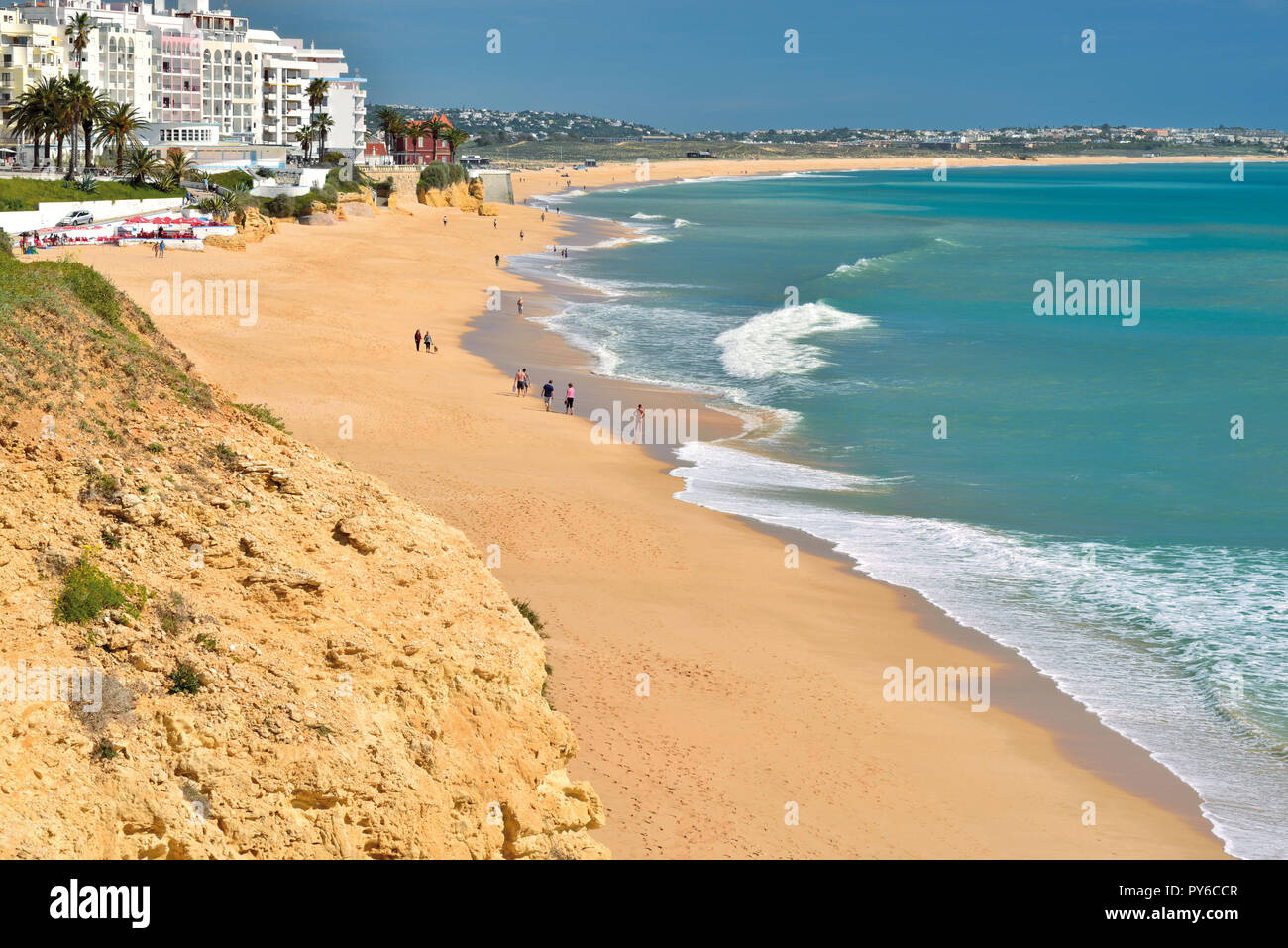 View of long  beach curve with people walking in the sand  and apartment buildings lining the ocean Stock Photo