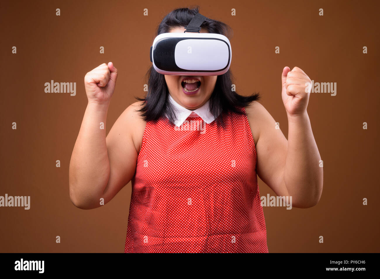 Excited overweight Asian woman using virtual reality VR glasses Stock Photo