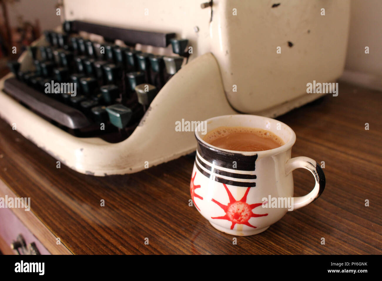 Translation: the vintage typewriter or type machine and a cup of chai tea. Perfect morning! Stock Photo