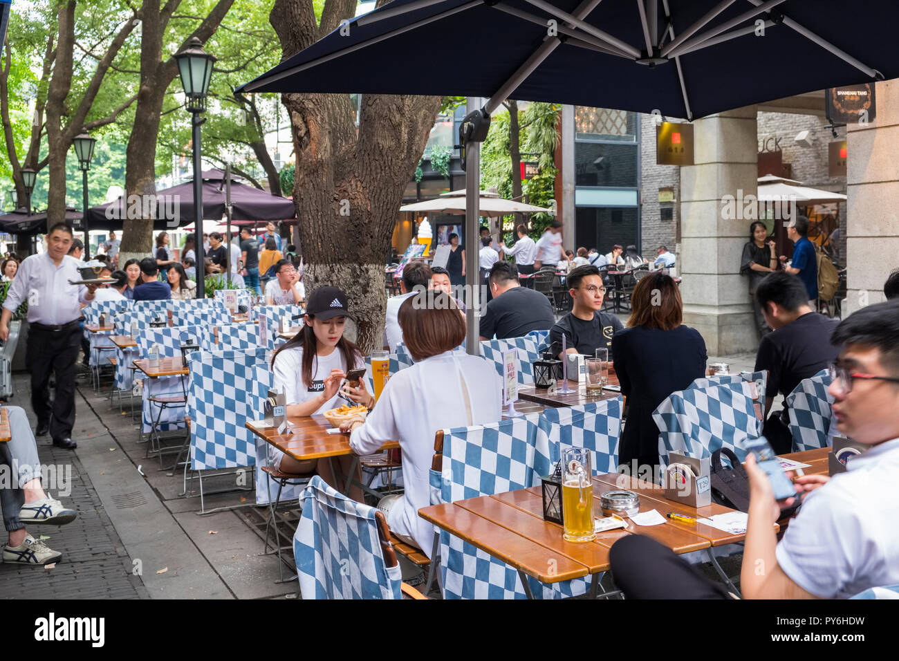 People eating and drinking at a pavement cafe restaurant outside in the Xintiandi development of the Old French Concession, Shanghai, China, Asia Stock Photo