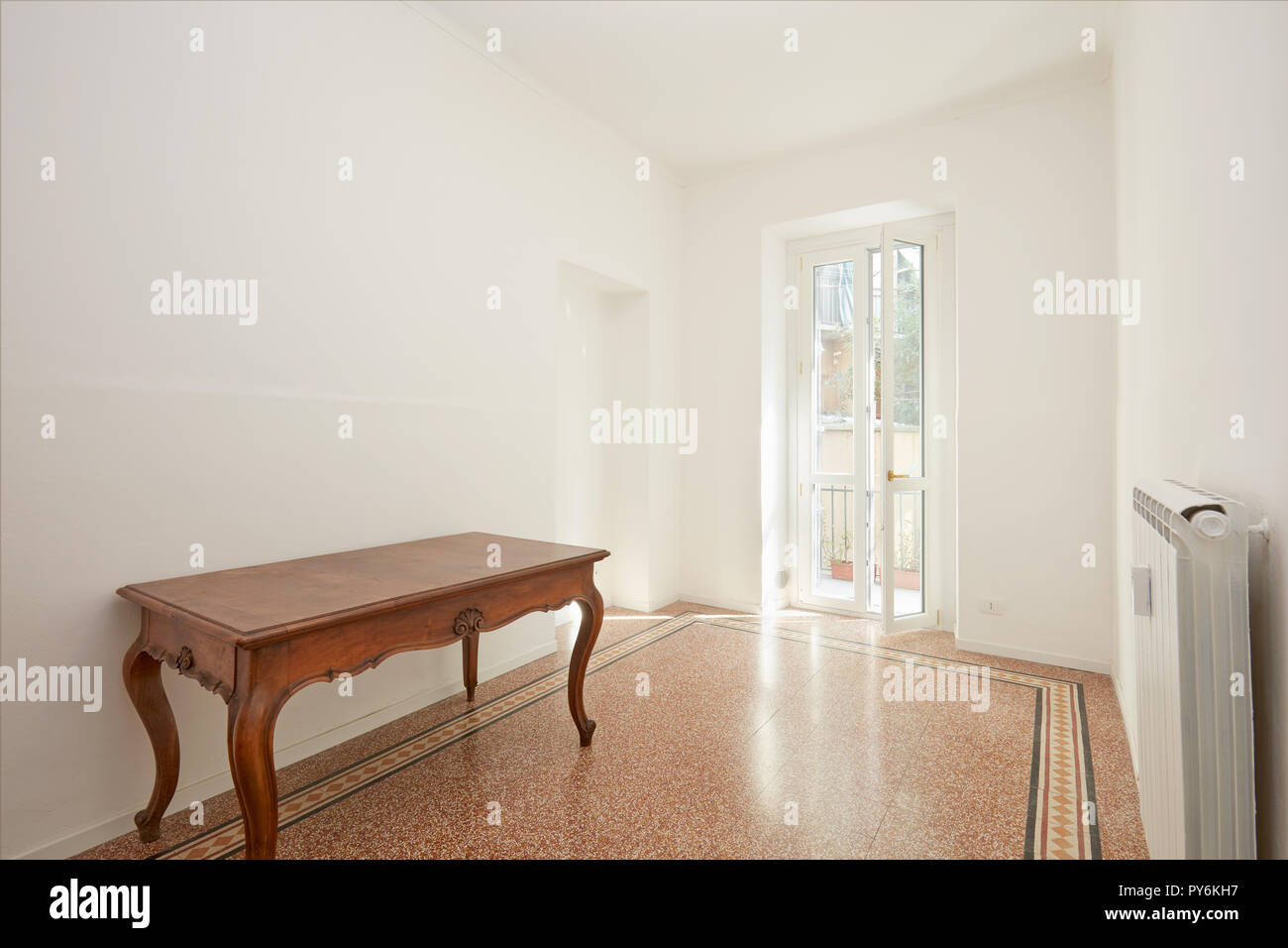 White room with wooden table in renovated apartment in a sunny day Stock Photo