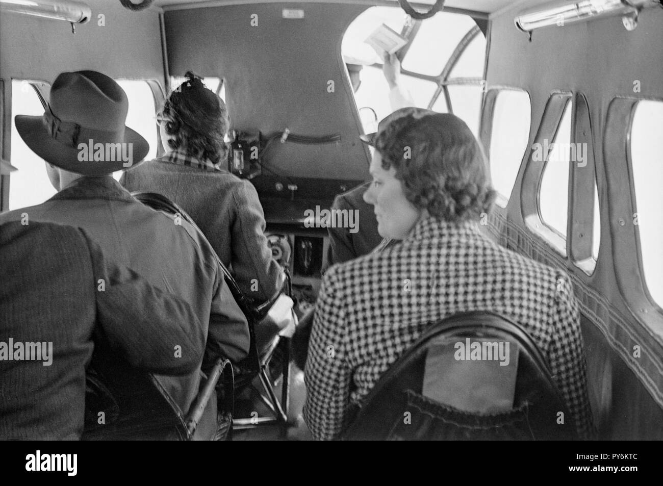 Black and white, vintage photograph showing four passengers inside the cabin of an aeroplane during the middle of the twentieth century. Stock Photo