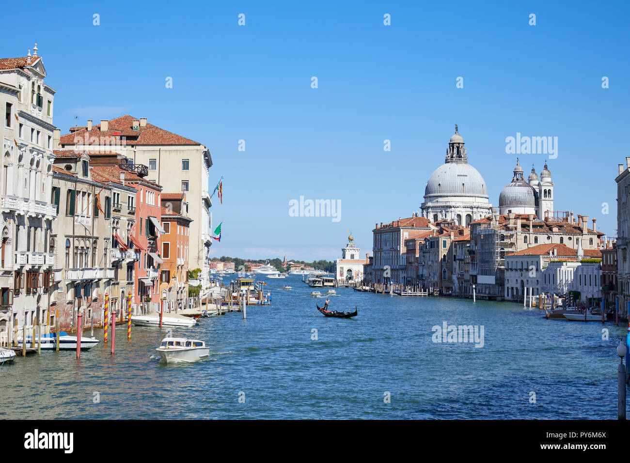 Grand Canal in Venice with gondola and Santa Maria della Salute basilica in Italy, blue sky Stock Photo