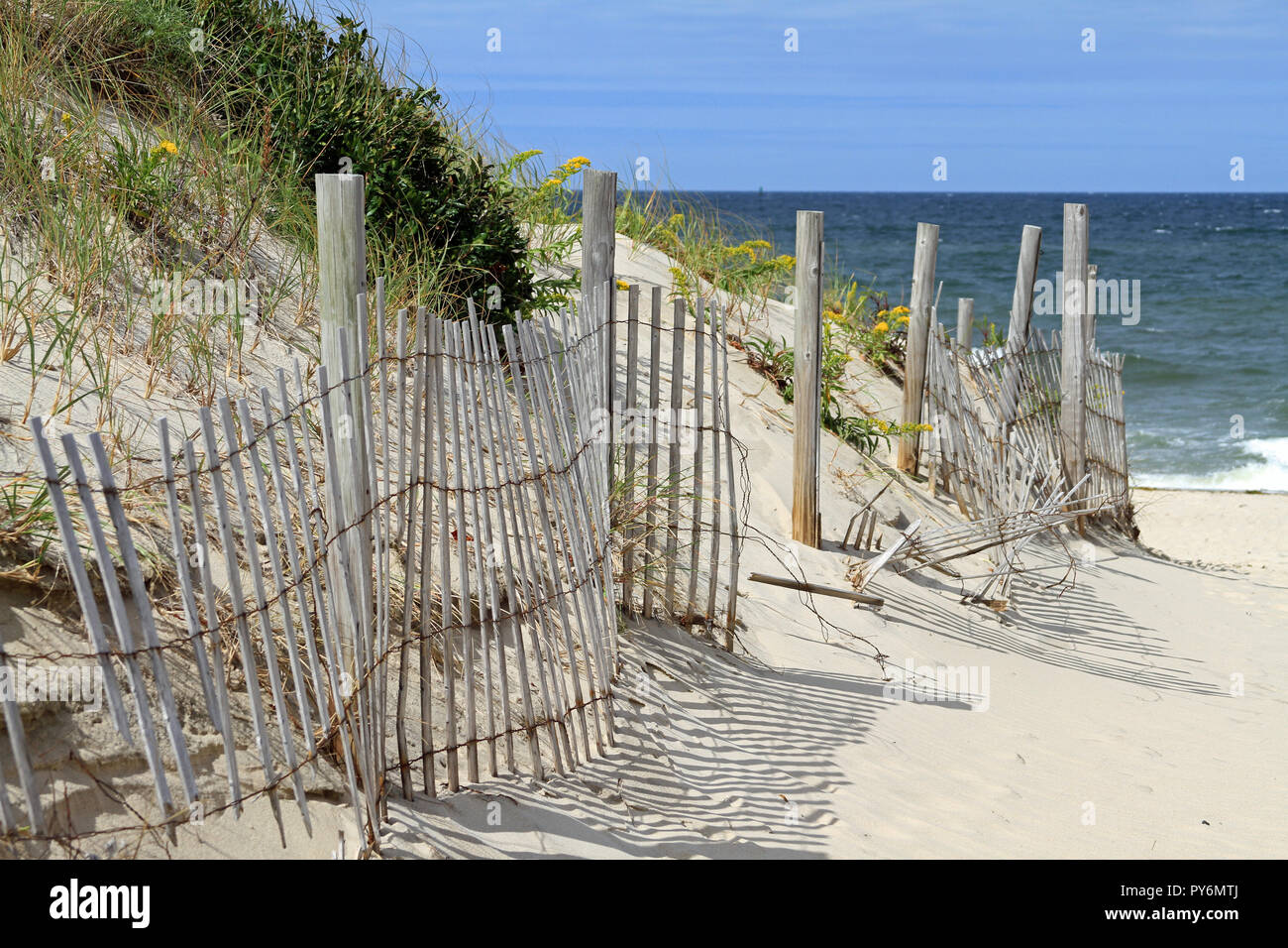 A rickety wooden fence protecting dunes along a sandy path that marks the entrance to Cold Storage Beach on Cape Cod in East Dennis, Massachusetts Stock Photo