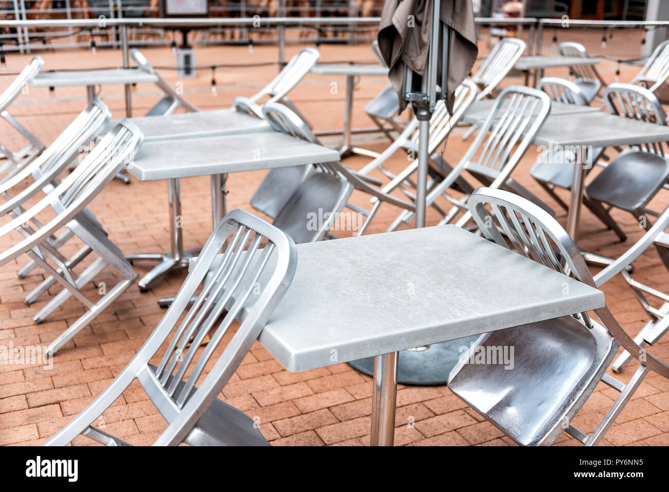 Many silver steel tables and chairs in closed cafe restaurant pattern outside outdoors, nobody, on street, closed umbrella Stock Photo